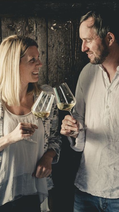 Lisa und Georg stoßen mit einem Glas Weißwein an
